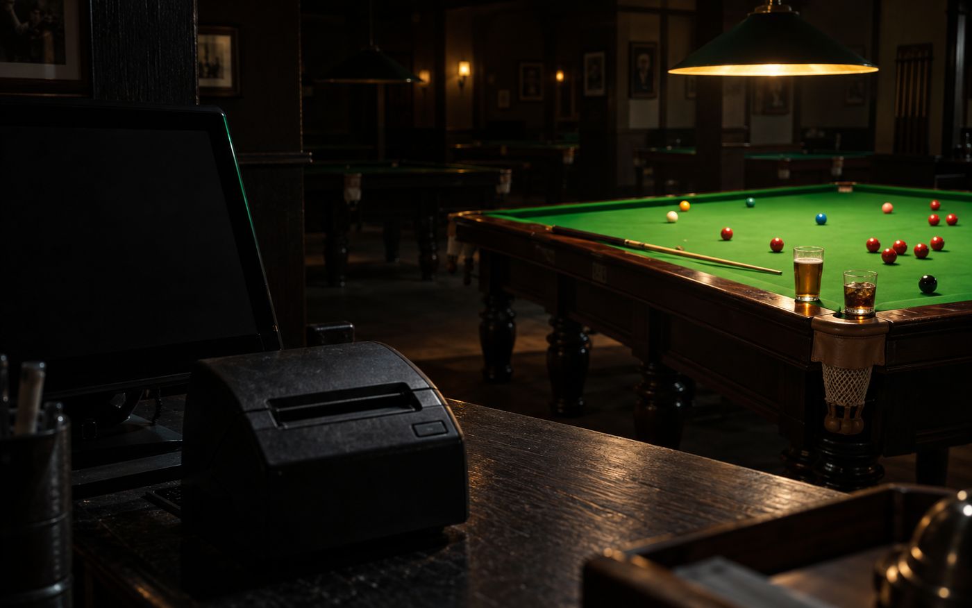 A snooker table lit and mid-game while the till screen beside it sits dark and the receipt printer stays empty - play that no invoice is recording